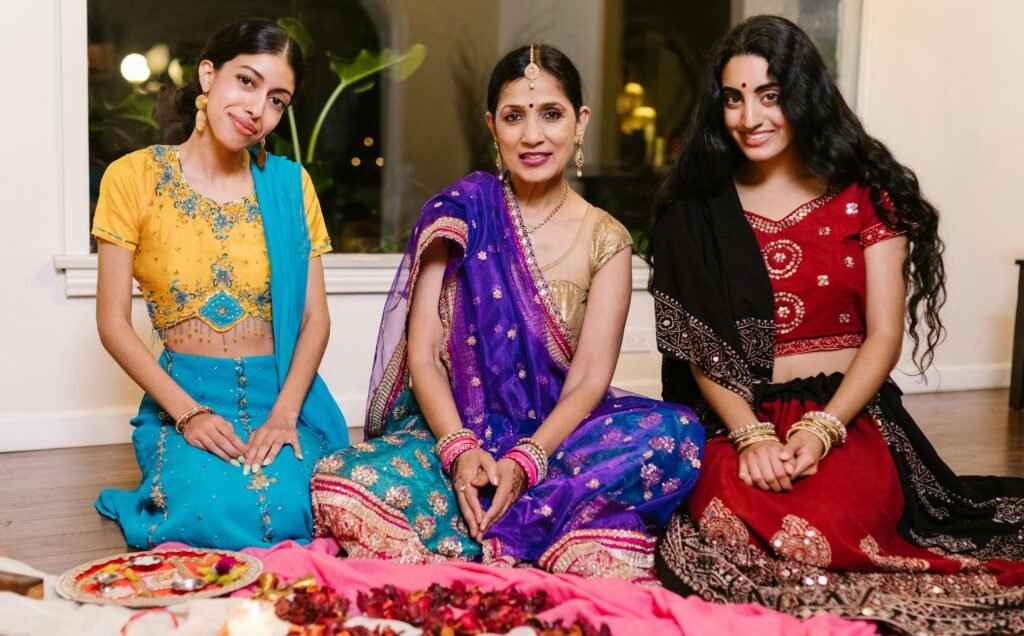 A group of women in colorful saris participating in an indoor cultural celebration.