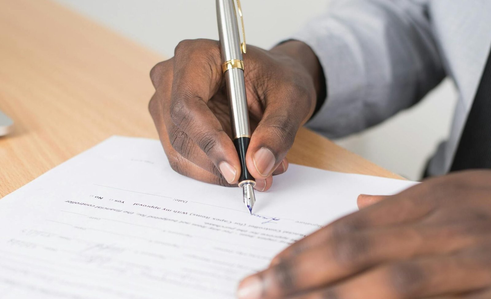 Close-up of a businessman signing a contract at an office desk.